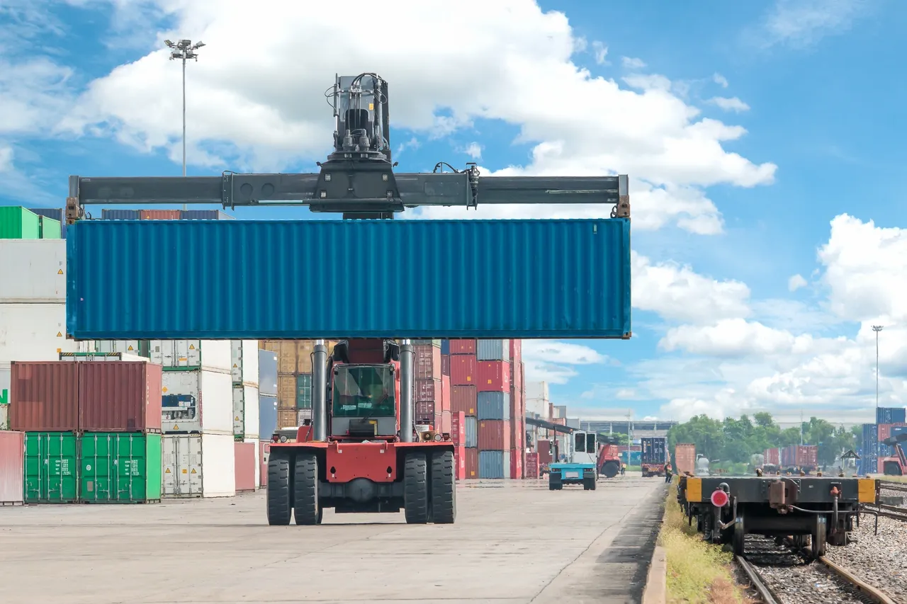 Container lifted by crane at shipping yard.