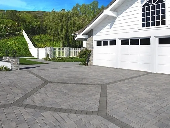 White house with paved driveway and greenery.