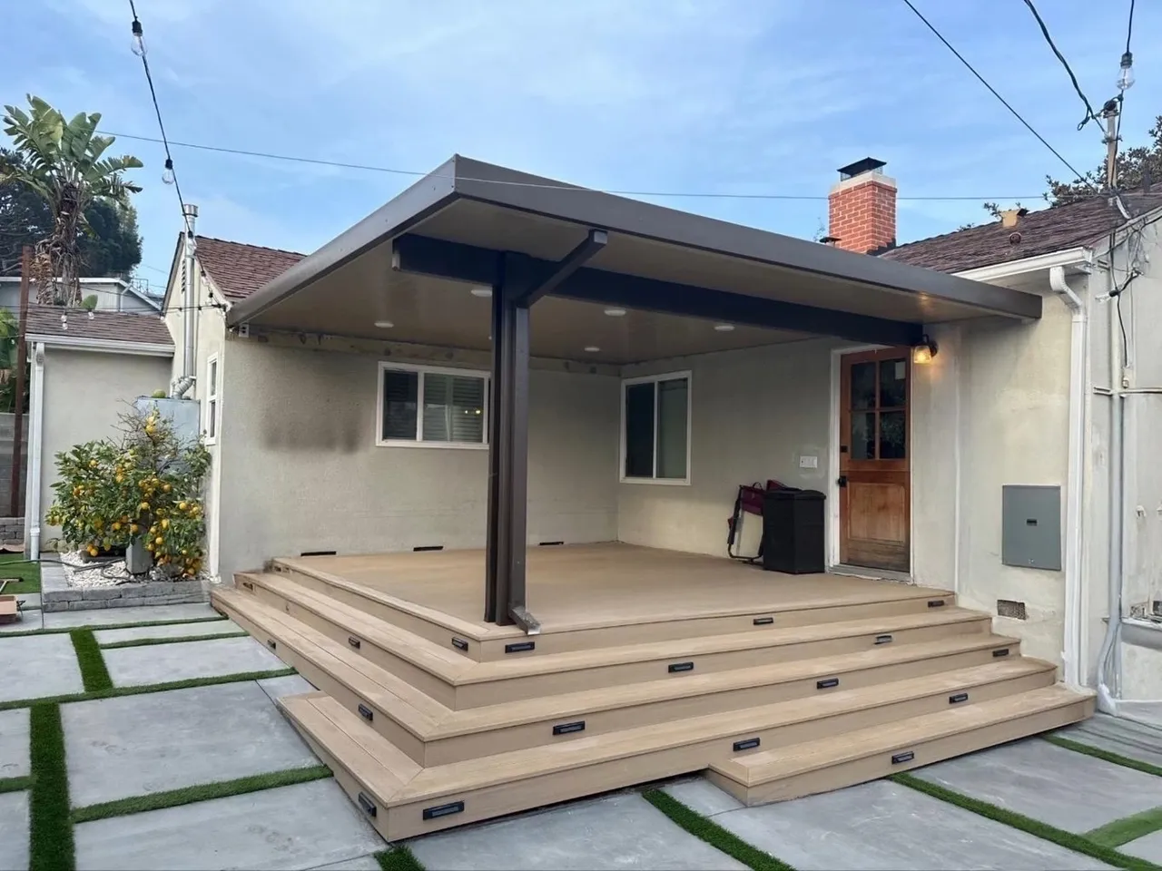 Covered patio with steps and concrete pathway.