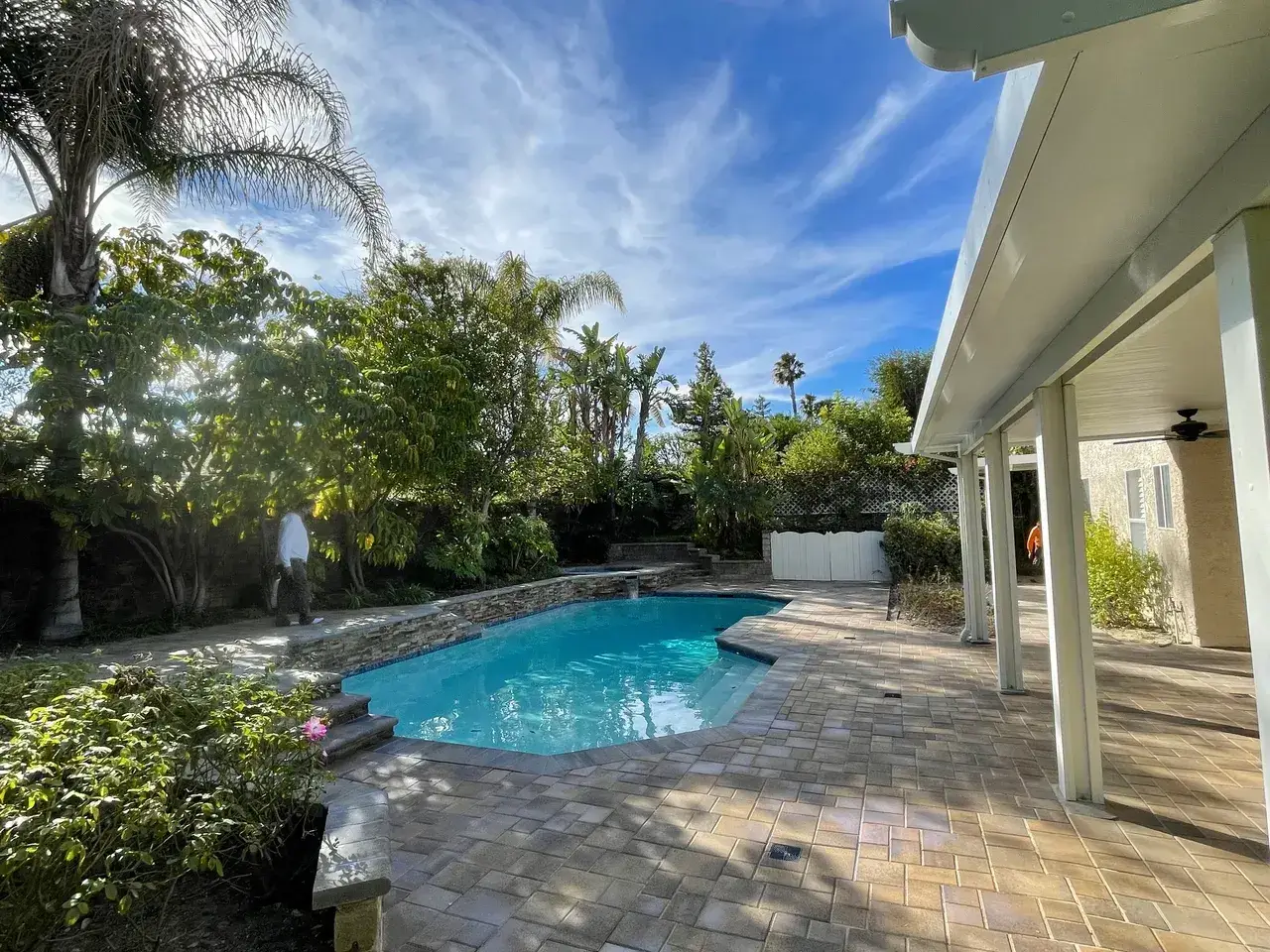 Backyard pool with patio and trees.