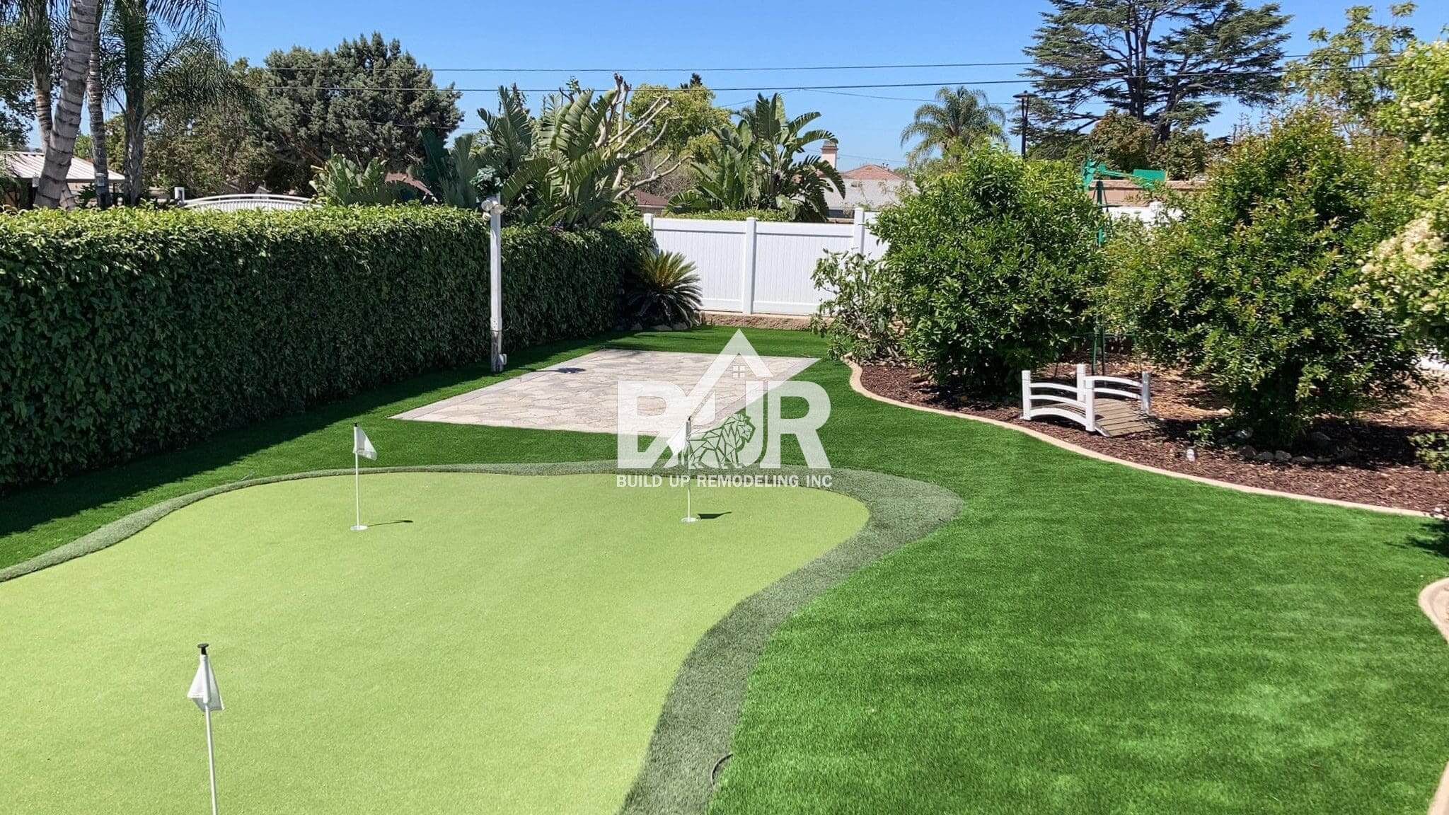 Backyard mini golf putting green under clear skies.