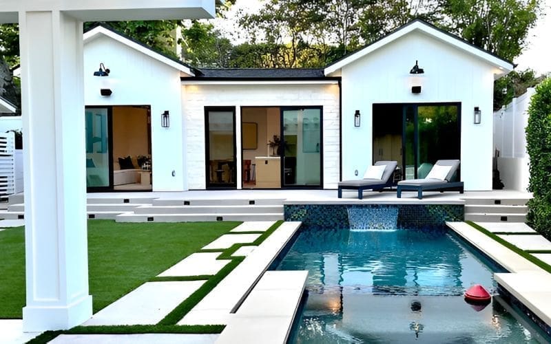 Modern white house with a pool and stepping stone pathway.