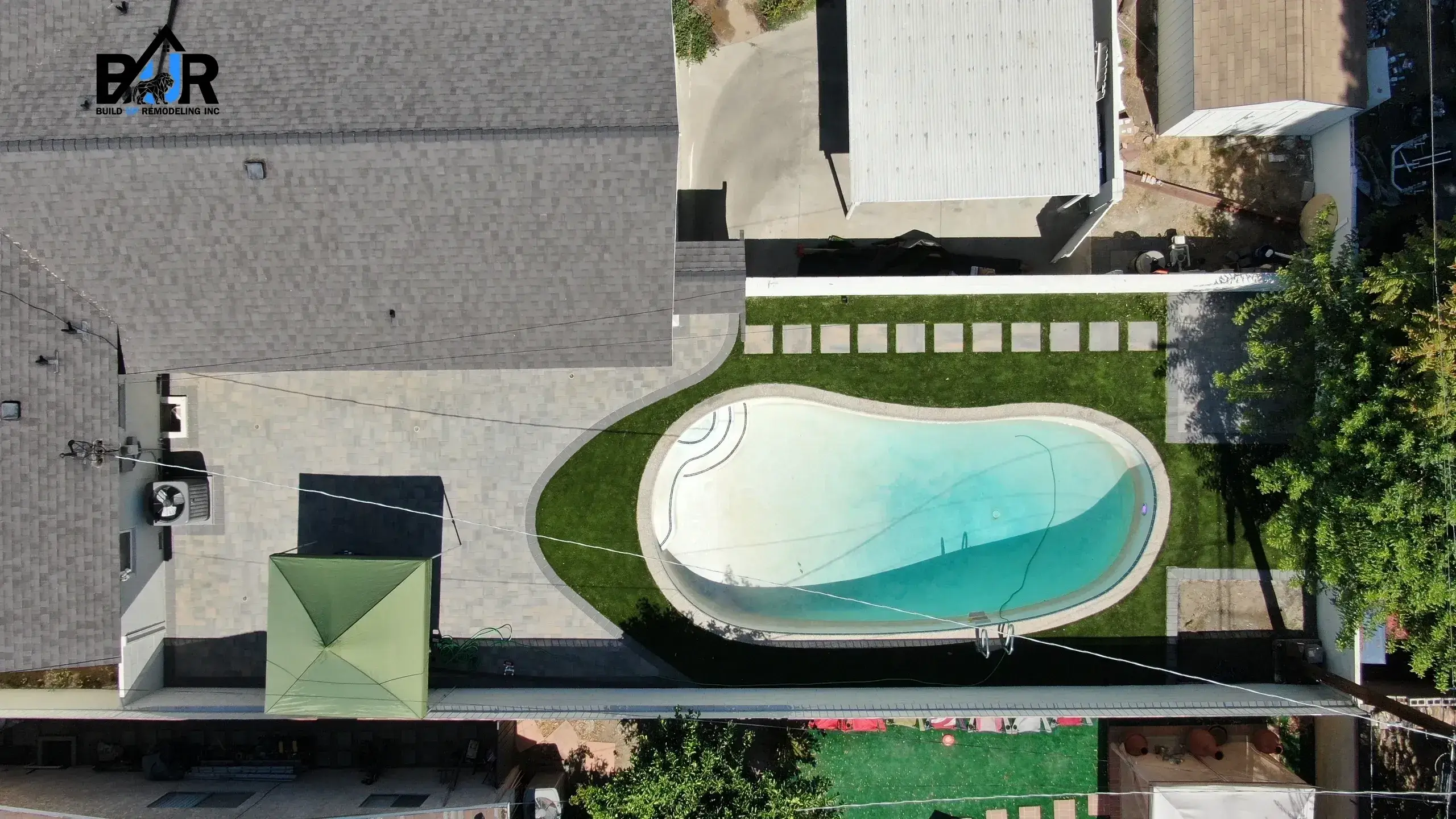 Aerial view of a backyard with an oval swimming pool and surrounding lawn.