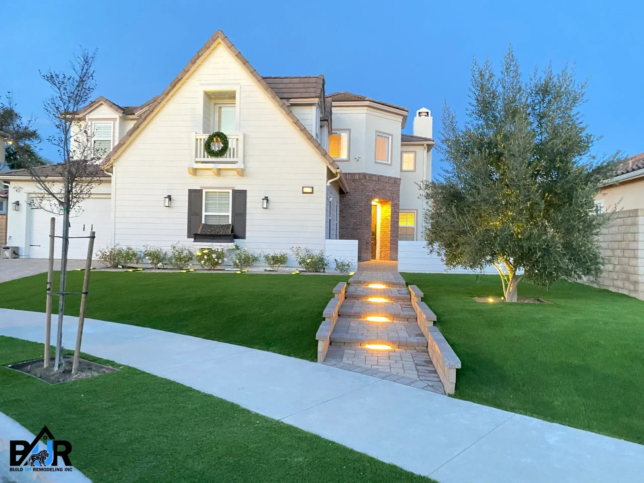 Cozy house with warm lighting and a welcoming front yard at dusk.
