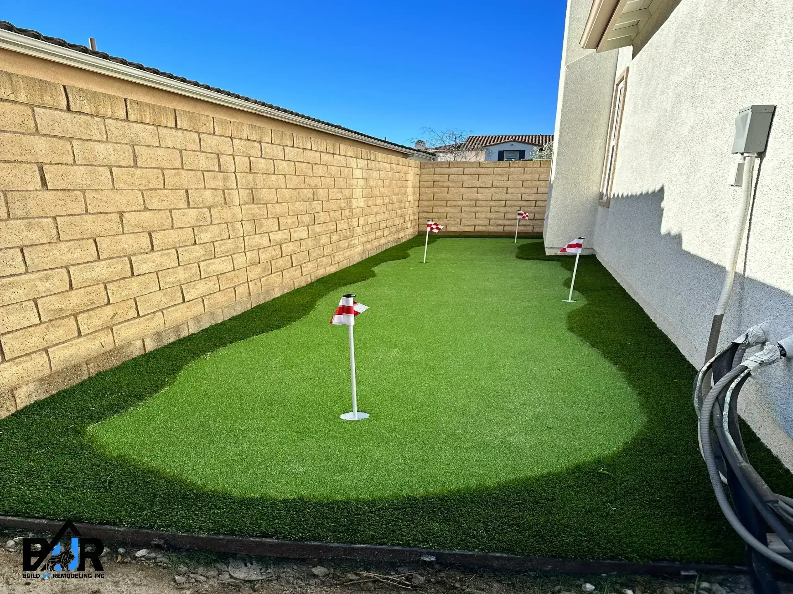 Small backyard putting green with two holes and flags.