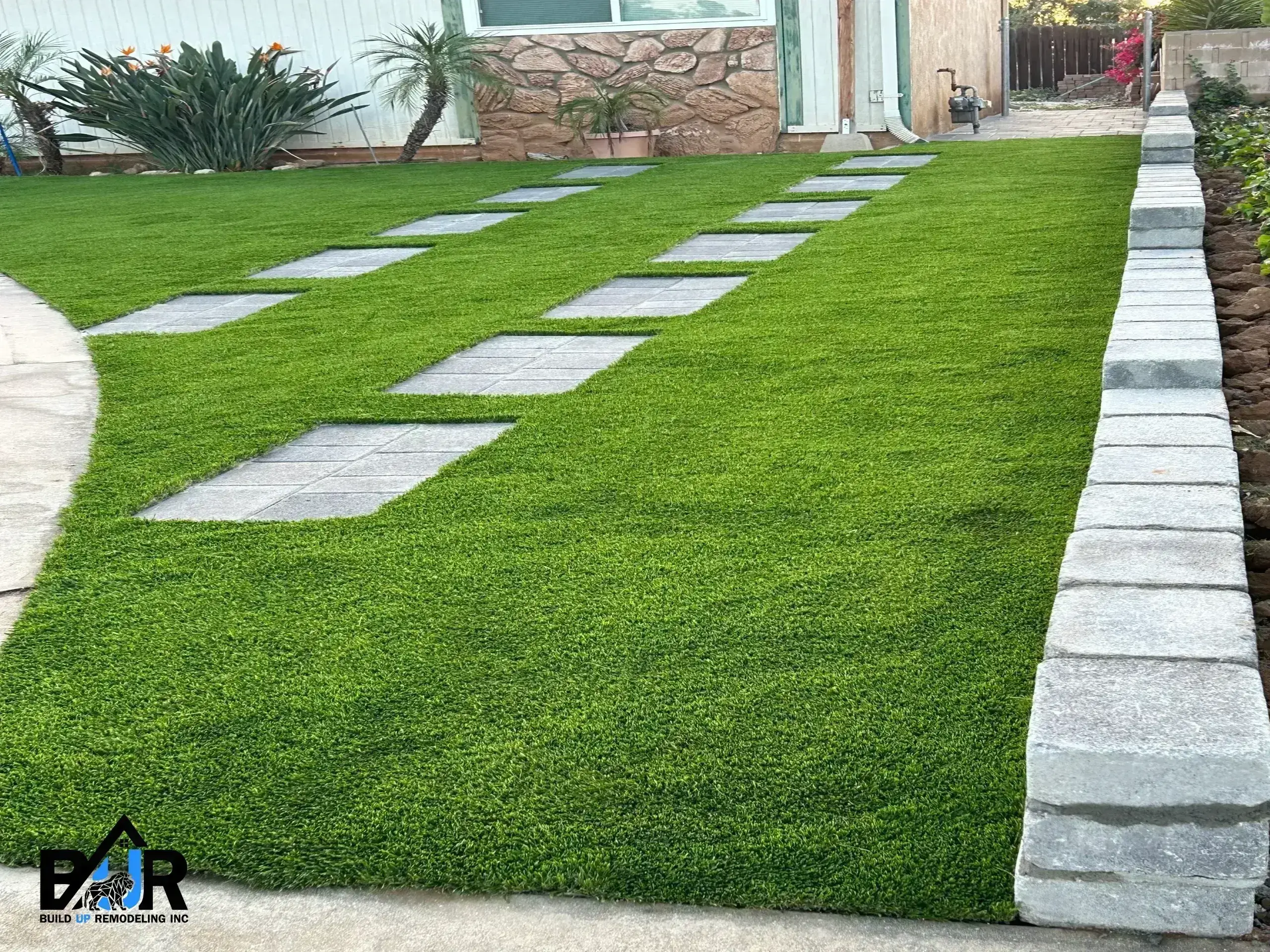 A neatly manicured lawn with stepping stones leading to a house.