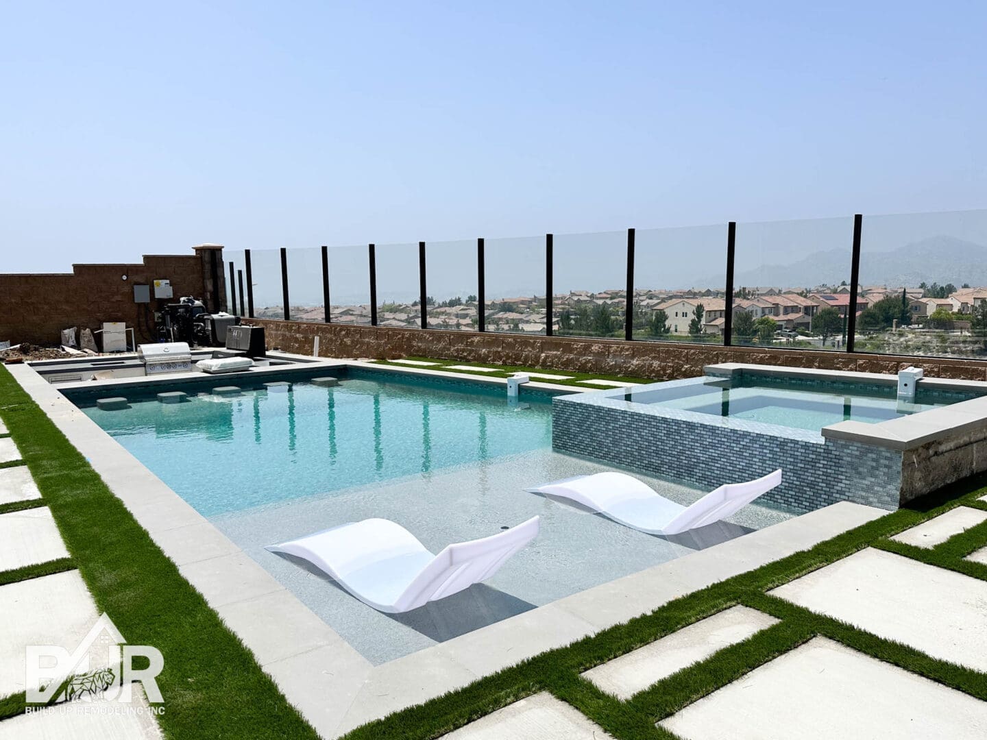 Rooftop pool with lounge chairs and view.