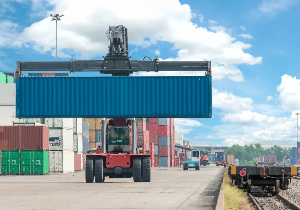 Container lifted by crane at shipping yard.