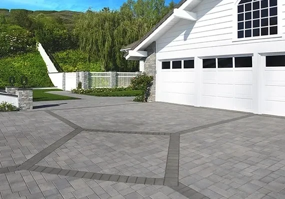 White house with paved driveway and greenery.